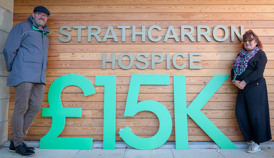 Strathcarron Hospice members stand next to oversized numbers indicating &#163;15k donated to the charity.